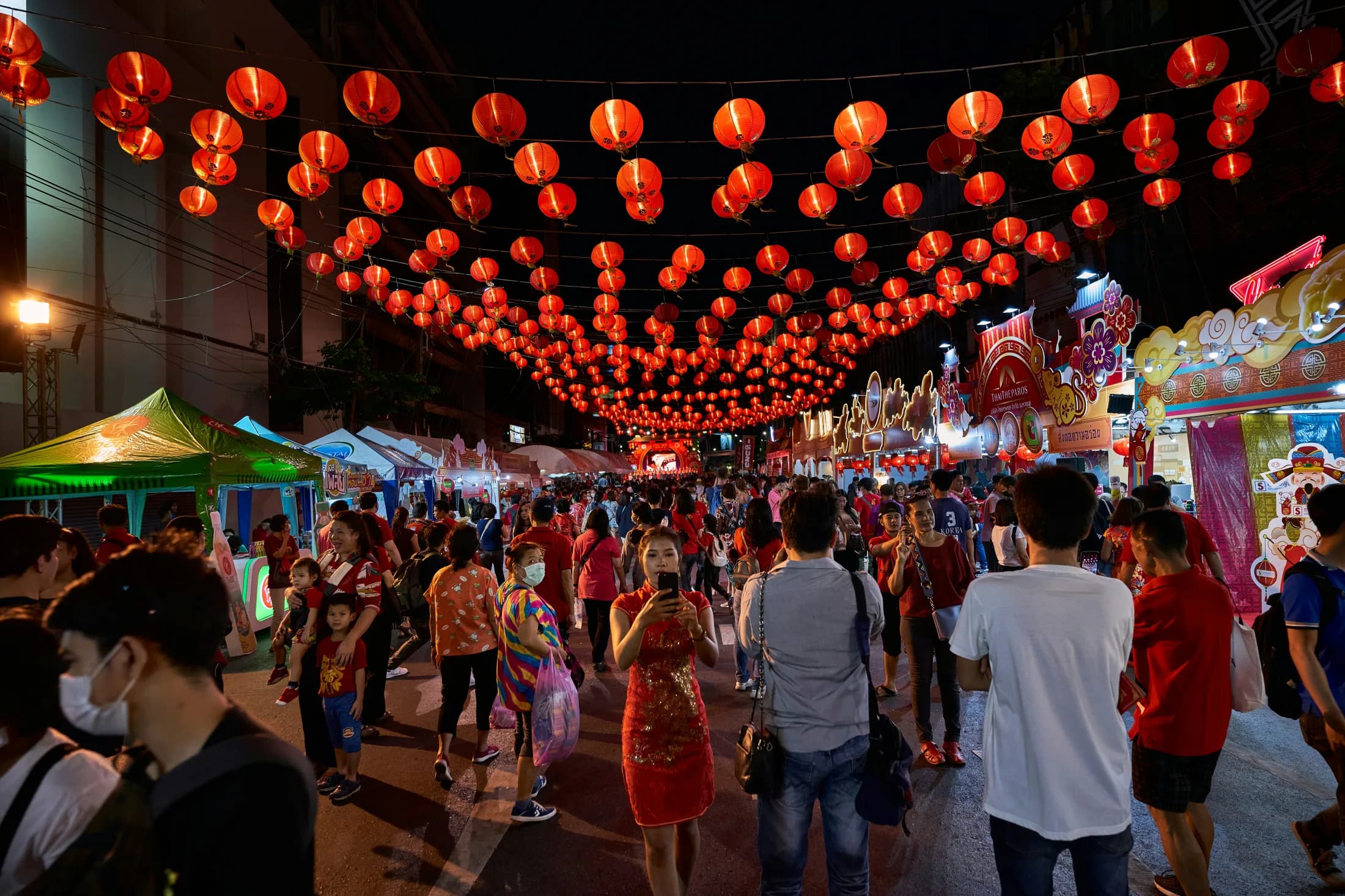 Festival crowds walking beneath red lanterns